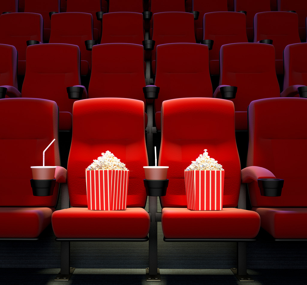 Empty theatre seats with 2 bags of popcorn in the two front seats.
