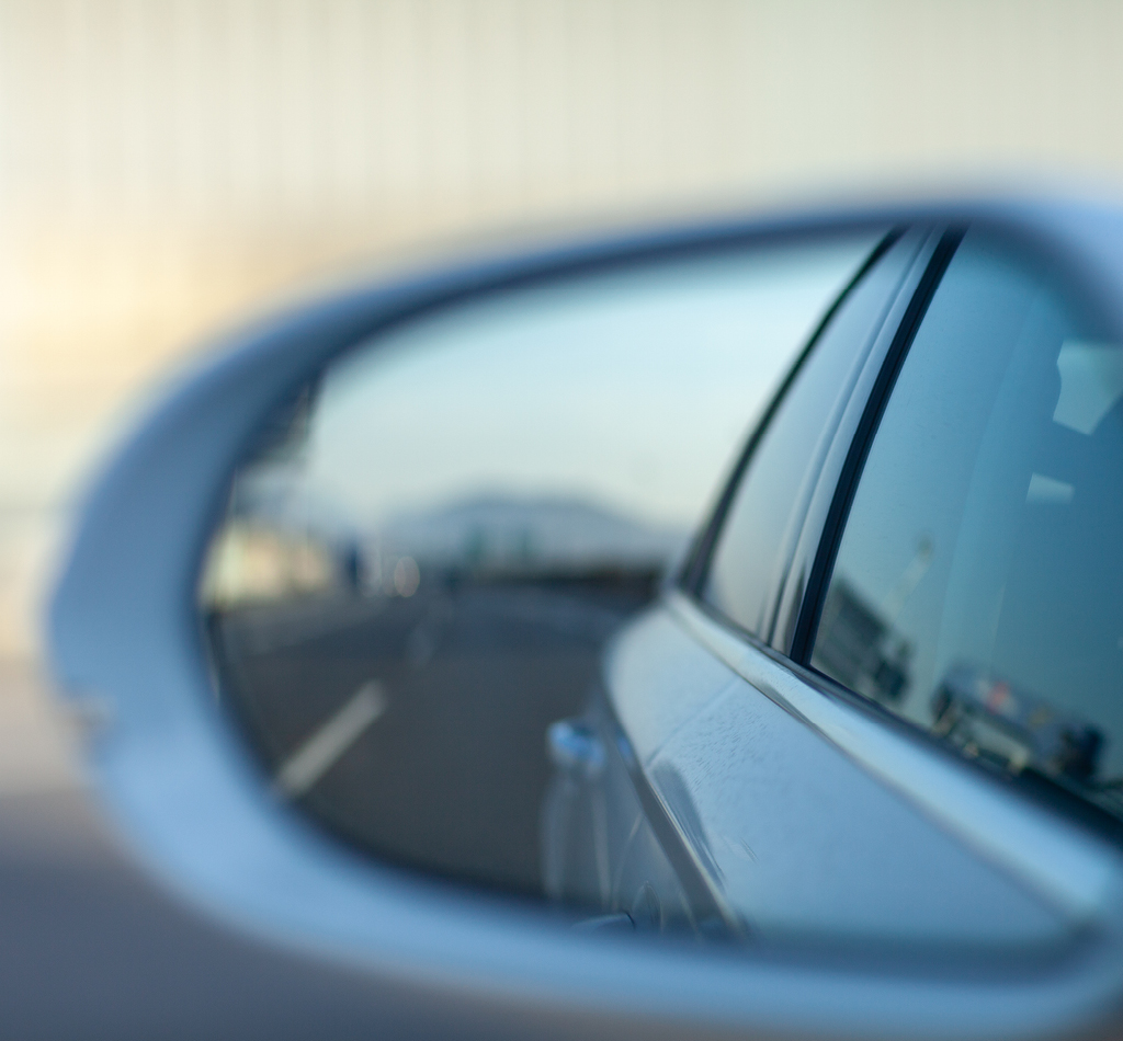 Image of car side mirror with view of scenery behind the car.